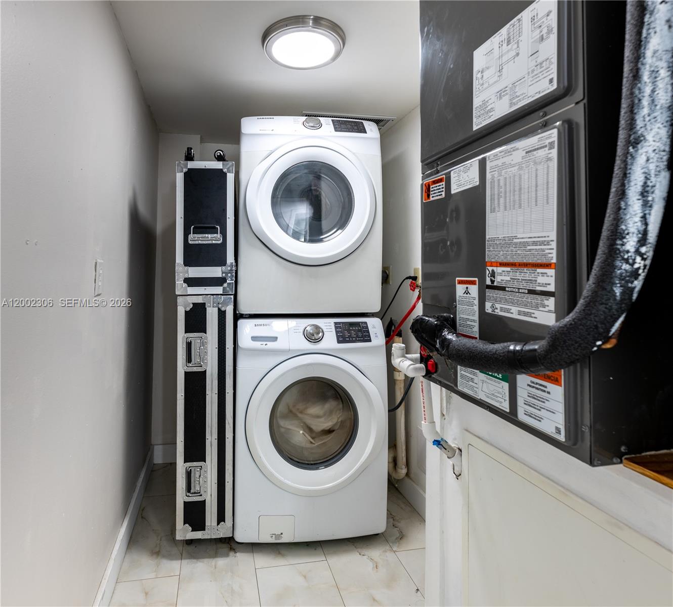 A laundry closet contains a stacked washer and dryer next to an HVAC unit — 300 NW 42nd Ave # 610, Miami FL 33126, MIAMI, FL