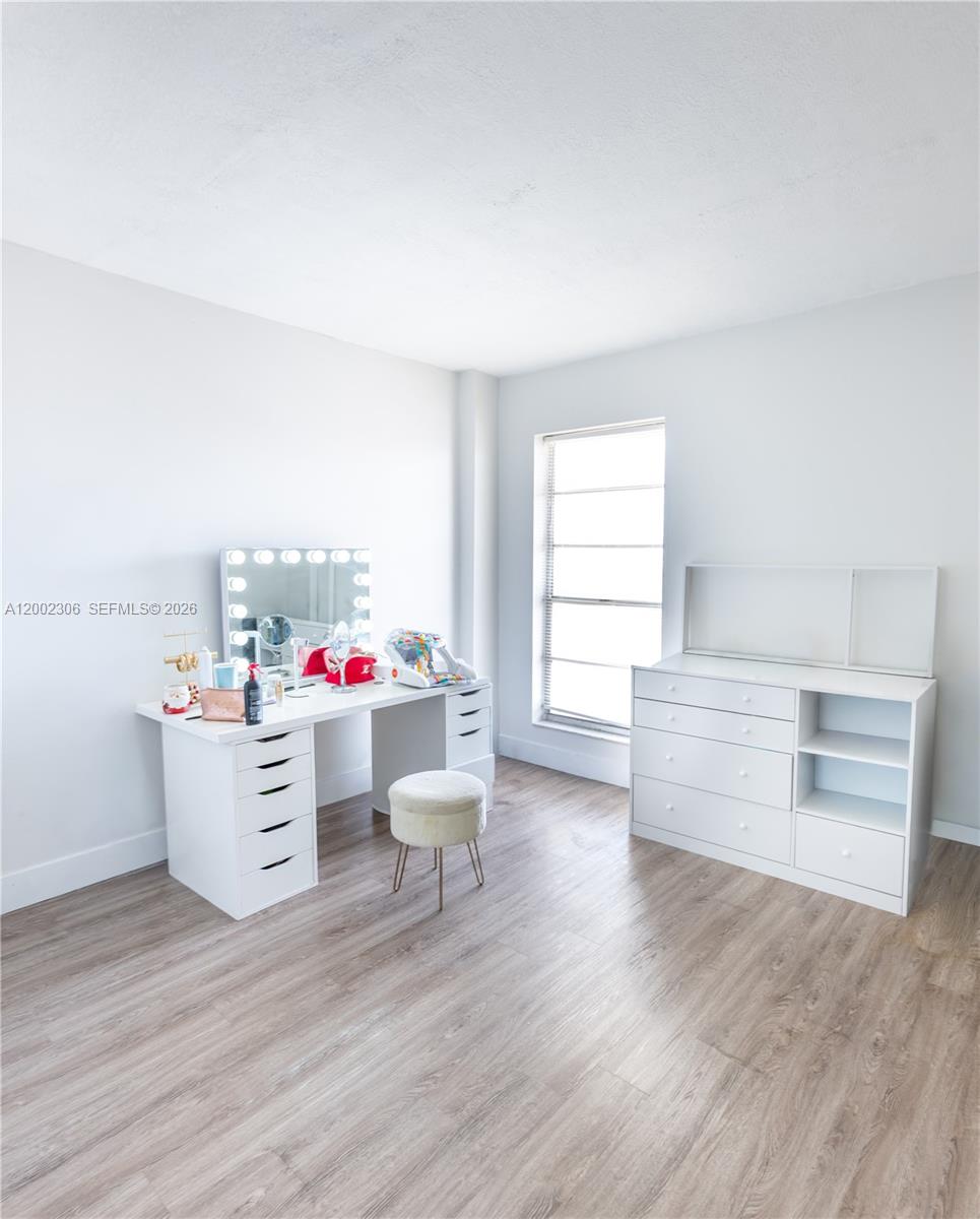 A bright room features a white vanity with a lighted mirror and a matching dresser — 300 NW 42nd Ave # 610, Miami FL 33126, MIAMI, FL