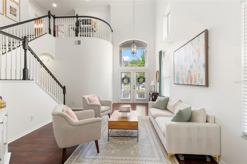 A bright living room features a high ceiling, a curved staircase, and a white sofa — 9706 GRETNA GREEN DRIVE, TAMPA, FL