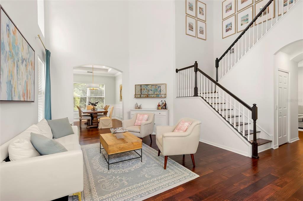 A living room with high ceilings, a staircase, and an adjacent dining area — 9706 GRETNA GREEN DRIVE, TAMPA, FL