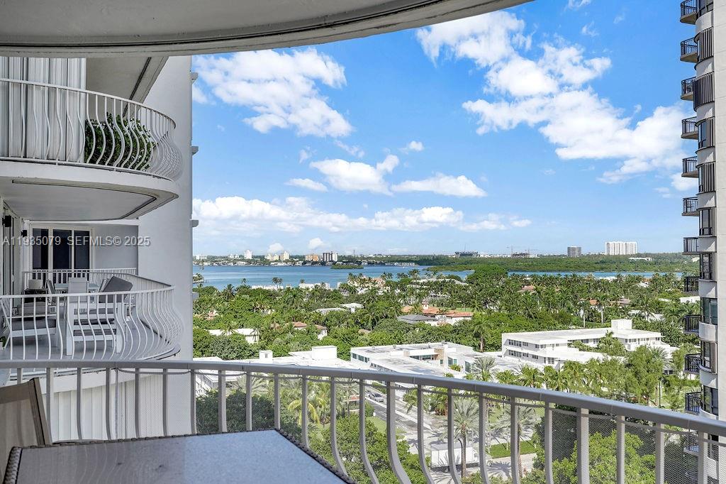 A high-rise balcony overlooks a lush landscape, a body of water, and distant buildings — 10155 Collins Ave # 1106, Bal Harbour FL 33154, BAL HARBOUR, FL