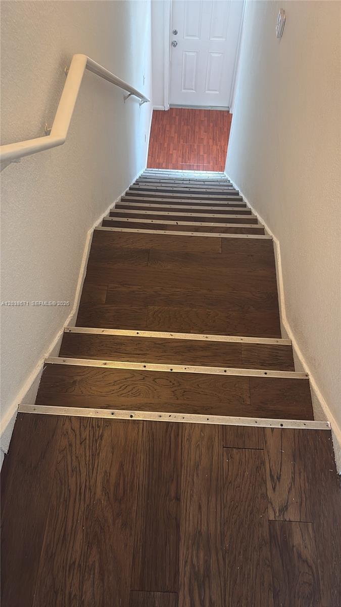 A staircase with dark wood-look flooring and metal stair nosing leads down to a door — 481 NW 84th Ln # 481, Miami FL 33150, MIAMI, FL