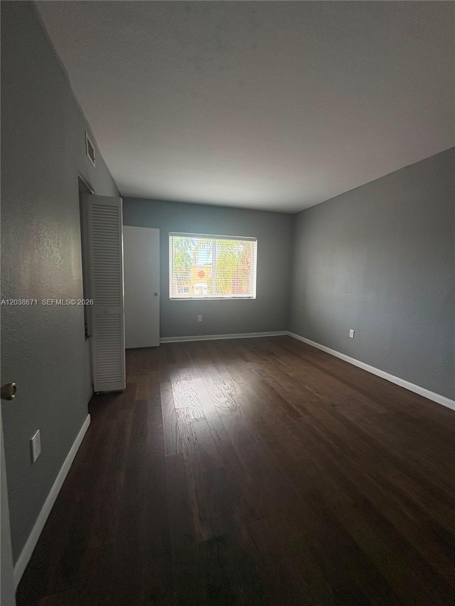 An empty bedroom features gray walls, dark wood-look flooring, and a single window — 481 NW 84th Ln # 481, Miami FL 33150, MIAMI, FL