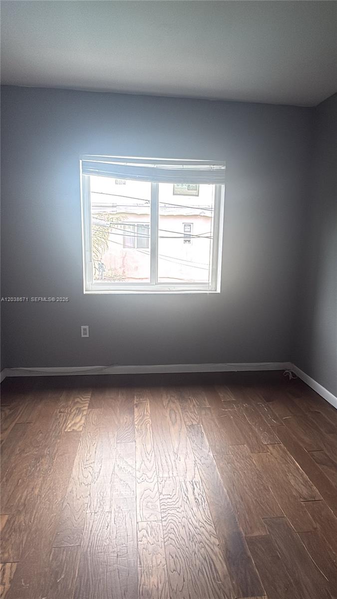 An empty room features gray walls, dark wood flooring, and a single window — 481 NW 84th Ln # 481, Miami FL 33150, MIAMI, FL