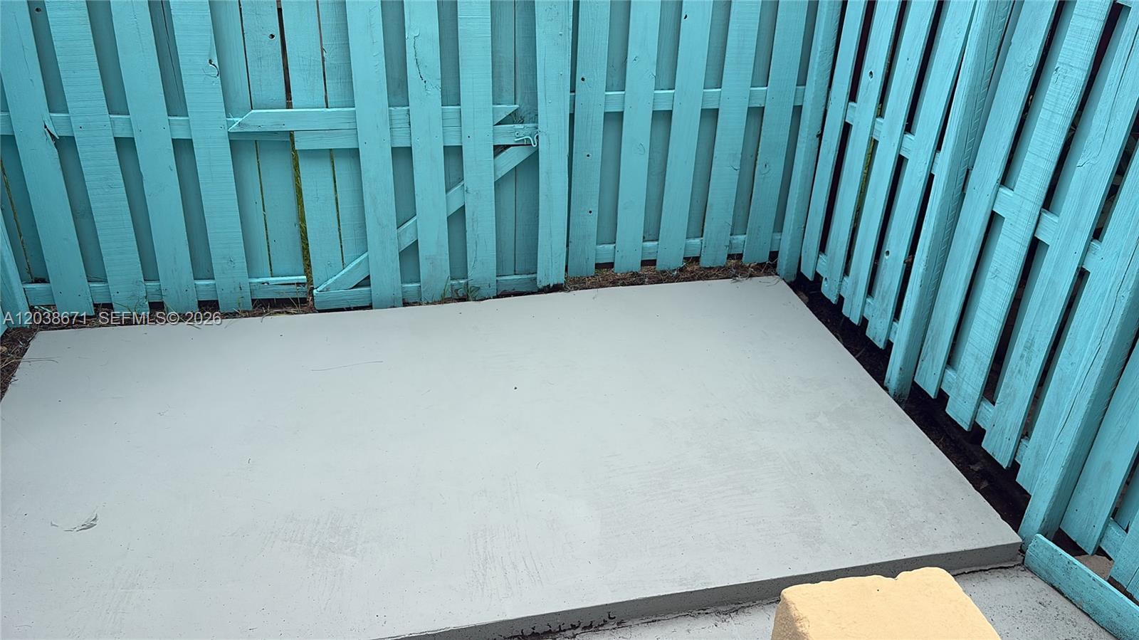 A concrete patio is enclosed by a light blue wooden privacy fence — 481 NW 84th Ln # 481, Miami FL 33150, MIAMI, FL