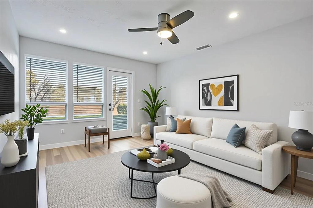 A bright living room features a white sofa, a round coffee table, and a ceiling fan — 9513 DARIEN AVENUE UNIT 9513, ORLANDO, FL
