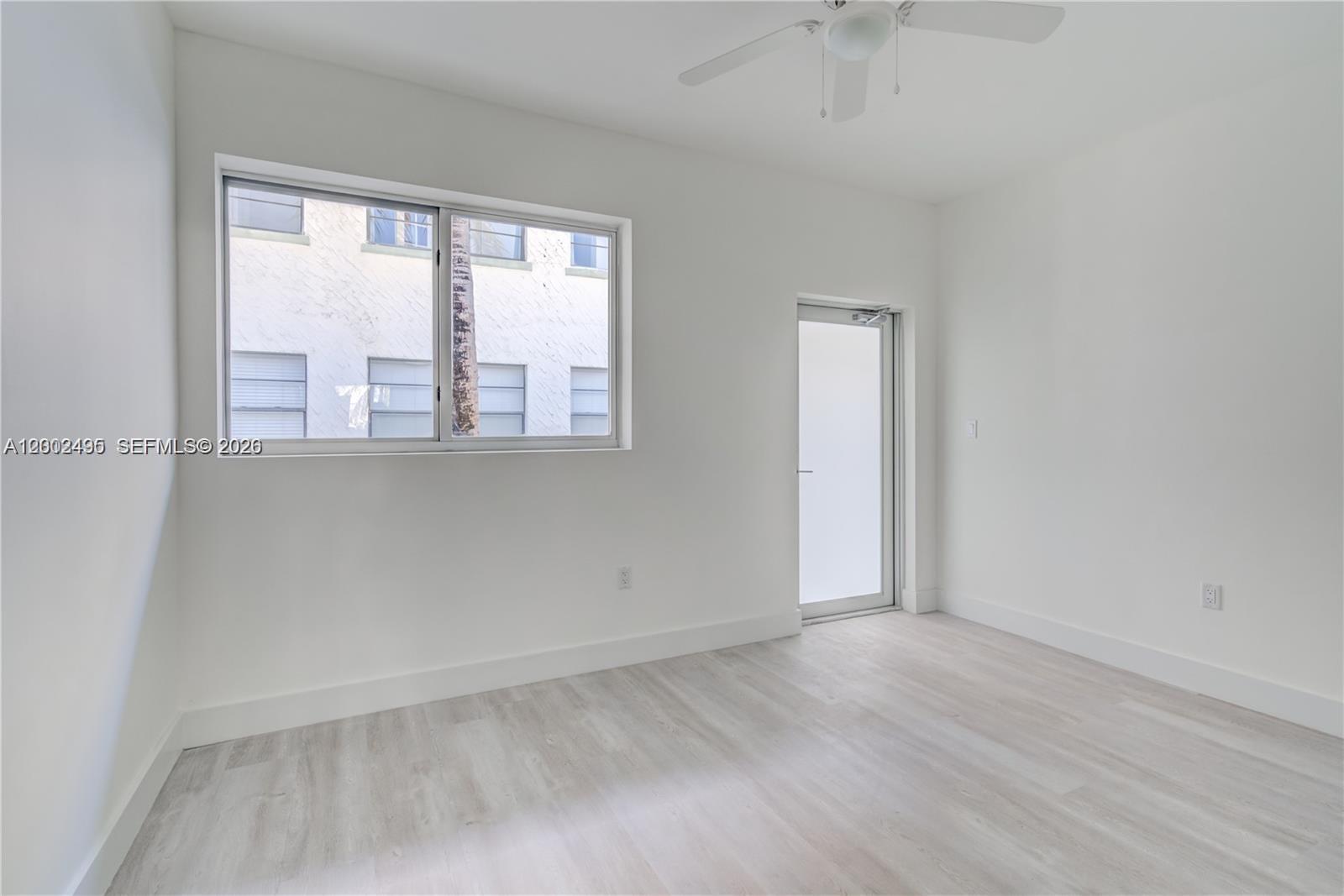 An empty room features white walls, light wood-look flooring, a ceiling fan, and a window — 940 Michigan Ave # 4, Miami Beach FL 33139, MIAMI BEACH, FL