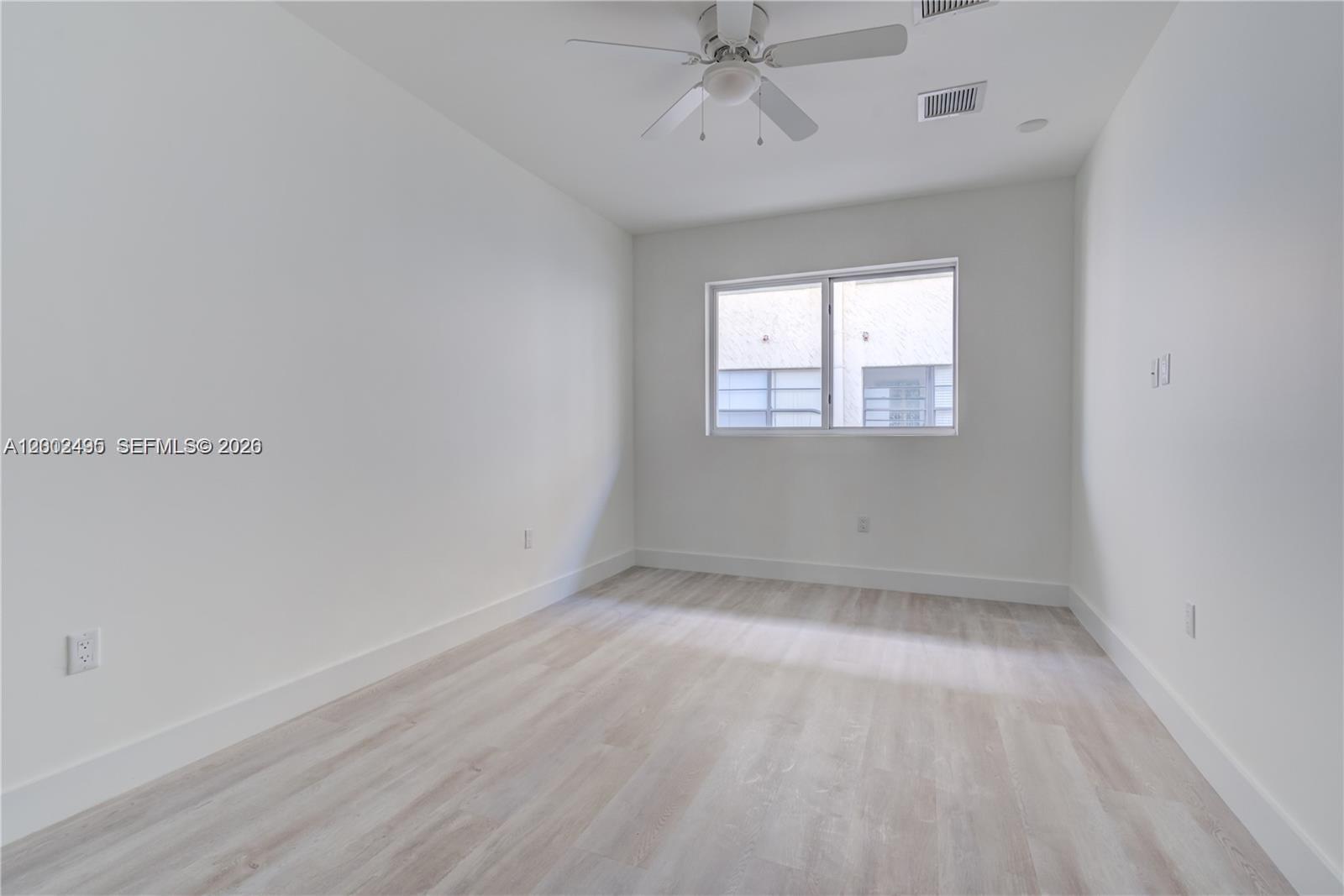 An empty room features white walls, light wood-look flooring, a ceiling fan, and a window — 940 Michigan Ave # 4, Miami Beach FL 33139, MIAMI BEACH, FL