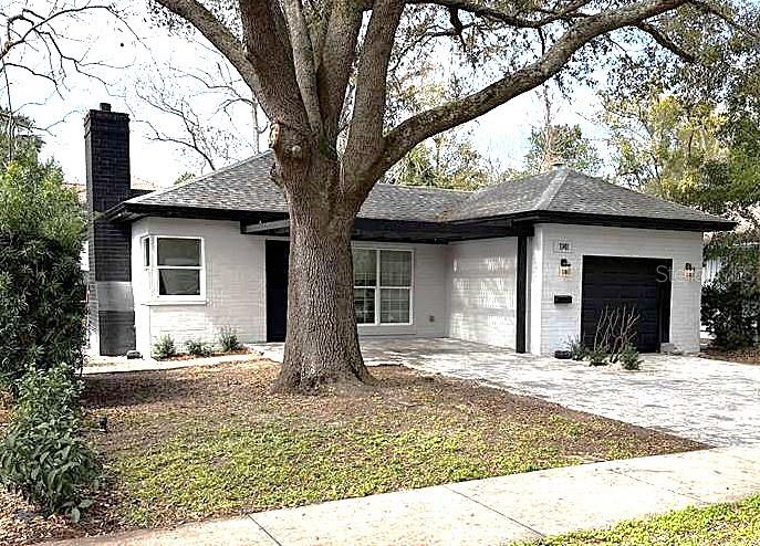 A white brick house with a black chimney and garage sits behind a large tree — 1741 LYNDALE BOULEVARD, MAITLAND, FL
