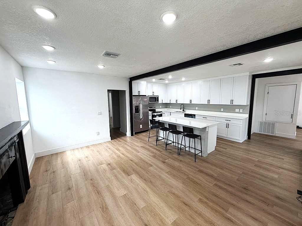A kitchen with white cabinets and a center island opens into a living area — 1741 LYNDALE BOULEVARD, MAITLAND, FL