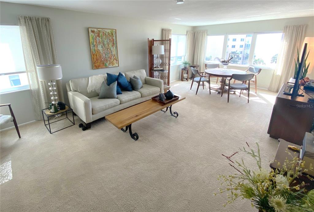 A living room features a beige sofa, wooden coffee table, dining area, and wall-to-wall carpeting — 500 THE ESPLANADE N UNIT 405, VENICE, FL