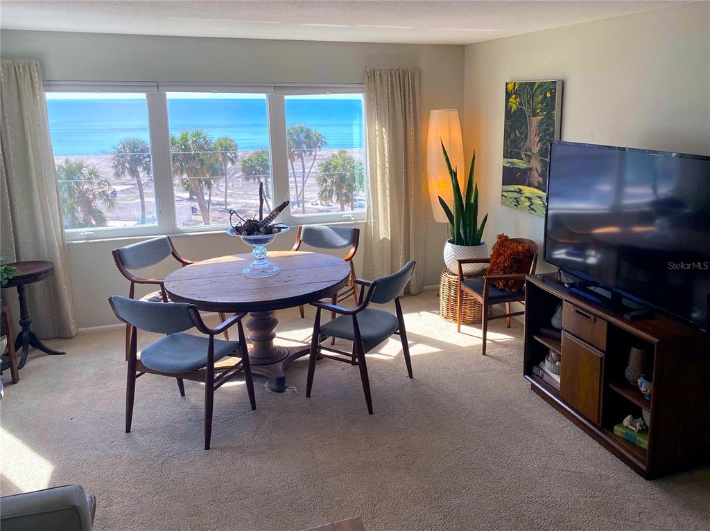 A dining area with a round wooden table and chairs overlooks a beach and ocean — 500 THE ESPLANADE N UNIT 405, VENICE, FL