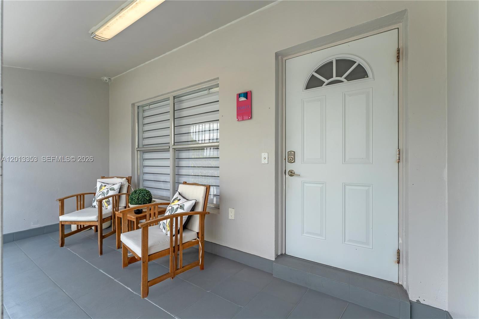 A covered porch features two wooden chairs, a small table, and a white front door — 6355 SW 30th St, Miami FL 33155, MIAMI, FL