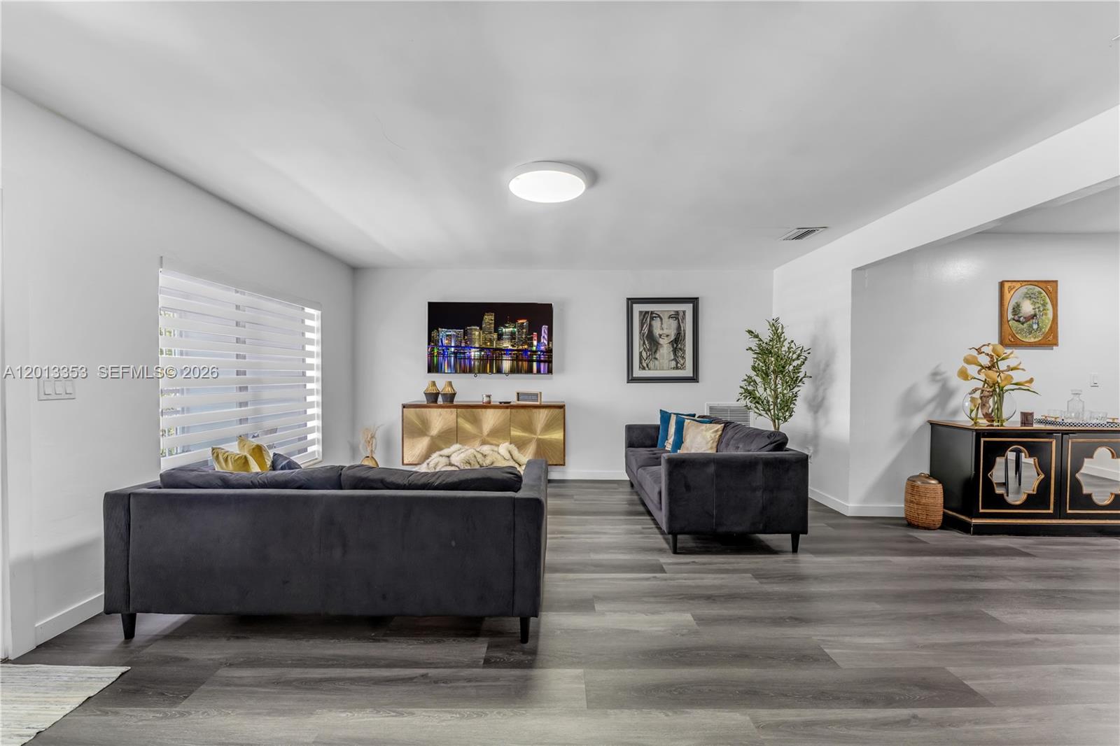 A living room features dark gray sofas, wood-look flooring, and a wall-mounted television — 6355 SW 30th St, Miami FL 33155, MIAMI, FL