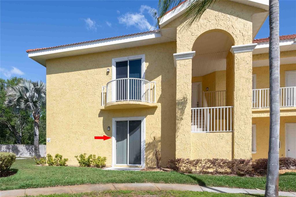 A two-story yellow stucco apartment building with a ground-floor sliding glass door and balcony — 21011 PICASSO COURT UNIT 106, LAND O LAKES, FL