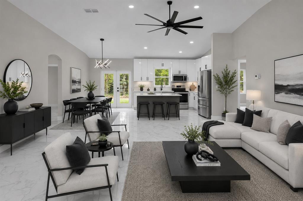 An open-concept living room and kitchen with white cabinets, marble floors, and modern furniture — 19060 SW 57TH PL, DUNNELLON, FL