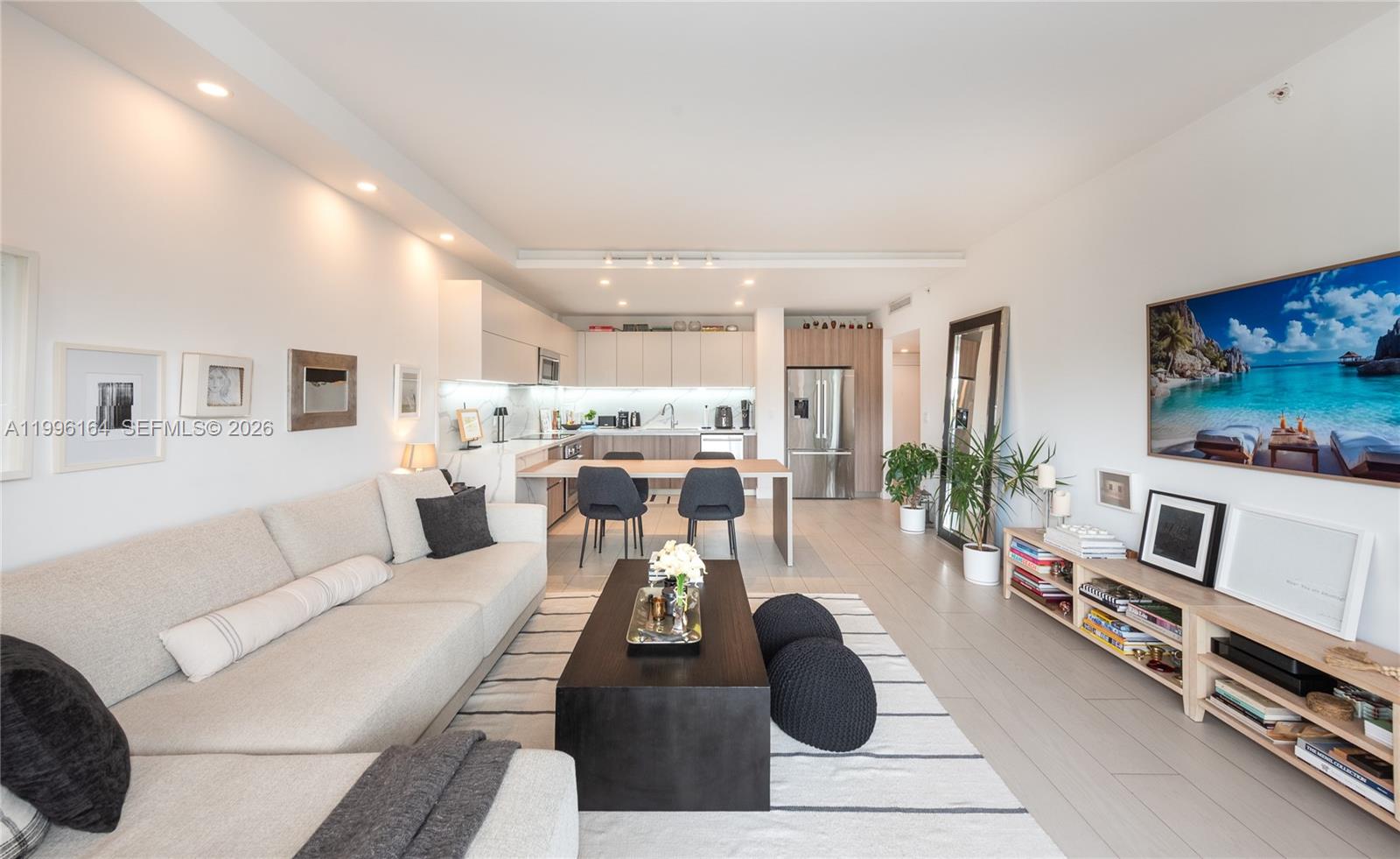 A modern open-concept living room and kitchen featuring light wood floors and neutral furniture — 151 Crandon Blvd # 241, Key Biscayne FL 33149, KEY BISCAYNE, FL