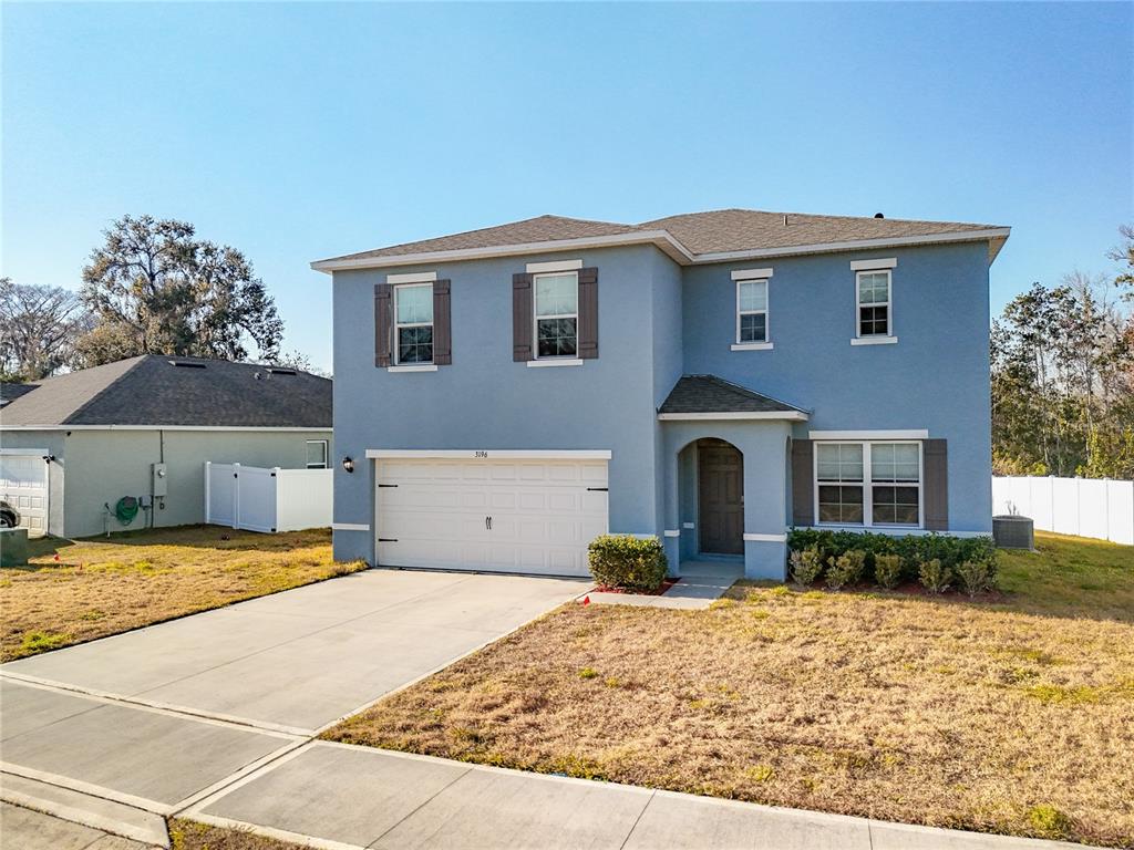 A two-story blue house with a white garage door and a concrete driveway — 3196 BLUE CRAB DRIVE, TAVARES, FL