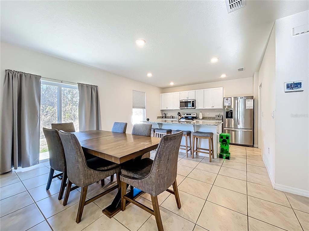 A dining area with a wooden table and chairs sits adjacent to an open kitchen — 3196 BLUE CRAB DRIVE, TAVARES, FL