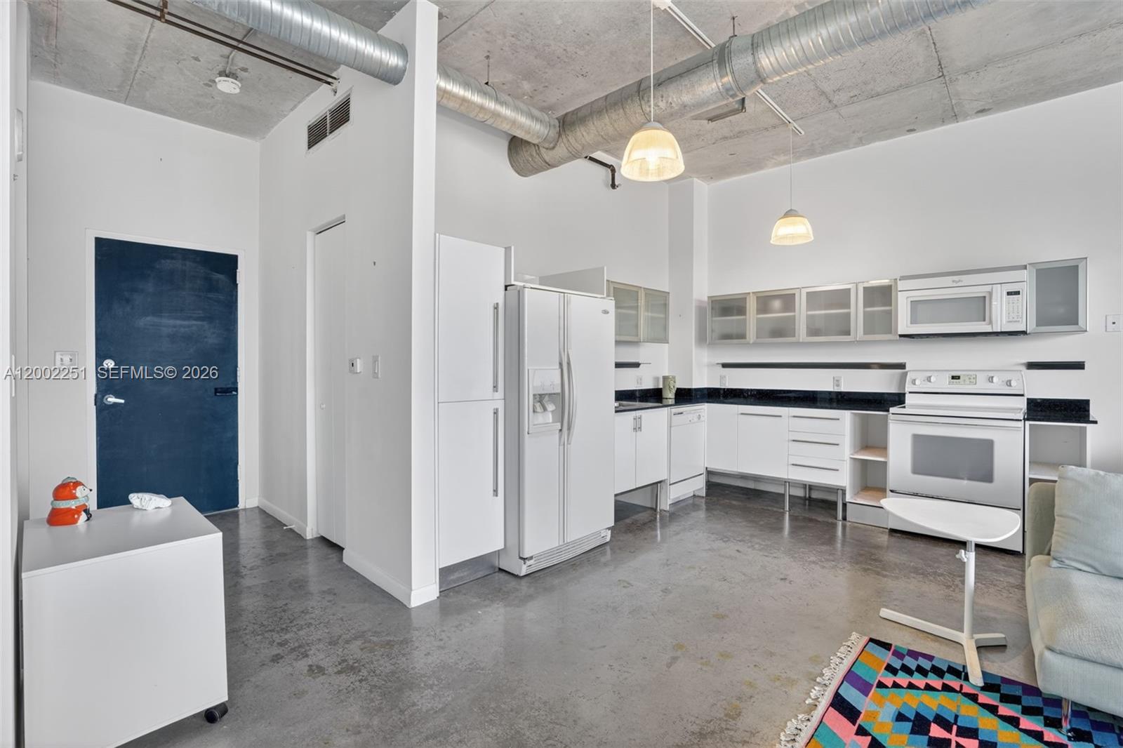 An industrial-style kitchen features concrete ceilings, exposed ductwork, white cabinetry, and polished concrete floors — 10 SW South River Dr # 1410, Miami FL 33130, MIAMI, FL