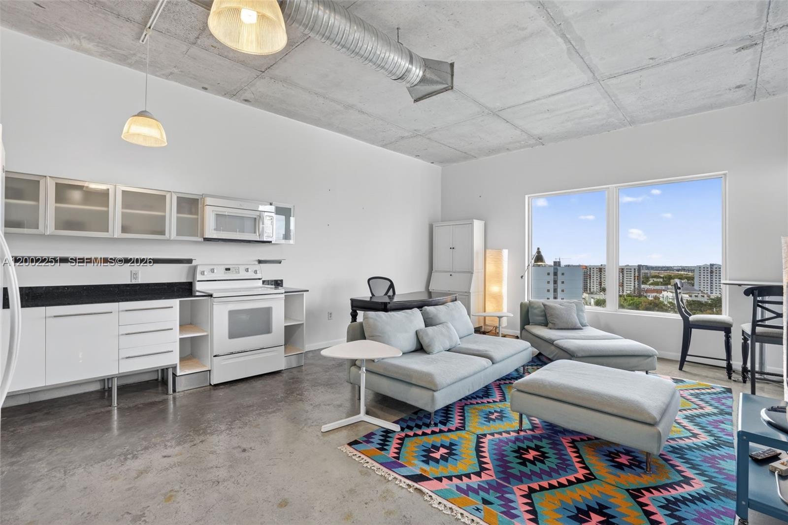 A studio apartment features a kitchen, living area, concrete ceiling, and large windows with views — 10 SW South River Dr # 1410, Miami FL 33130, MIAMI, FL