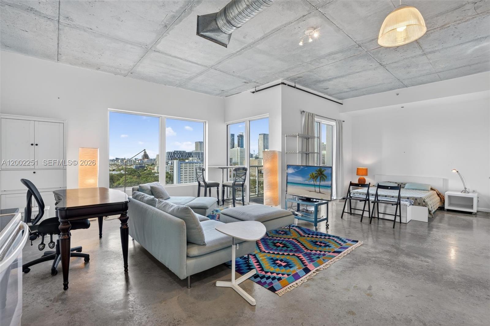 A studio apartment features a concrete ceiling, polished floors, and a view of city buildings — 10 SW South River Dr # 1410, Miami FL 33130, MIAMI, FL