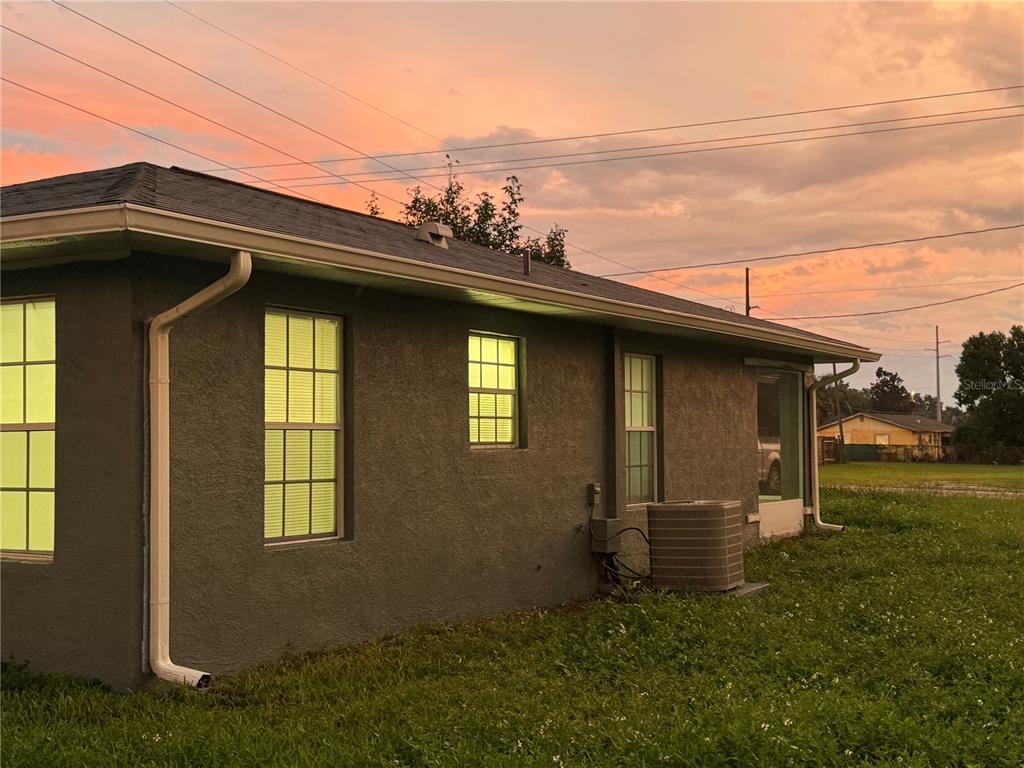 The exterior of a gray stucco house features multiple windows and an air conditioning unit — 37209 LOCK STREET, DADE CITY, FL