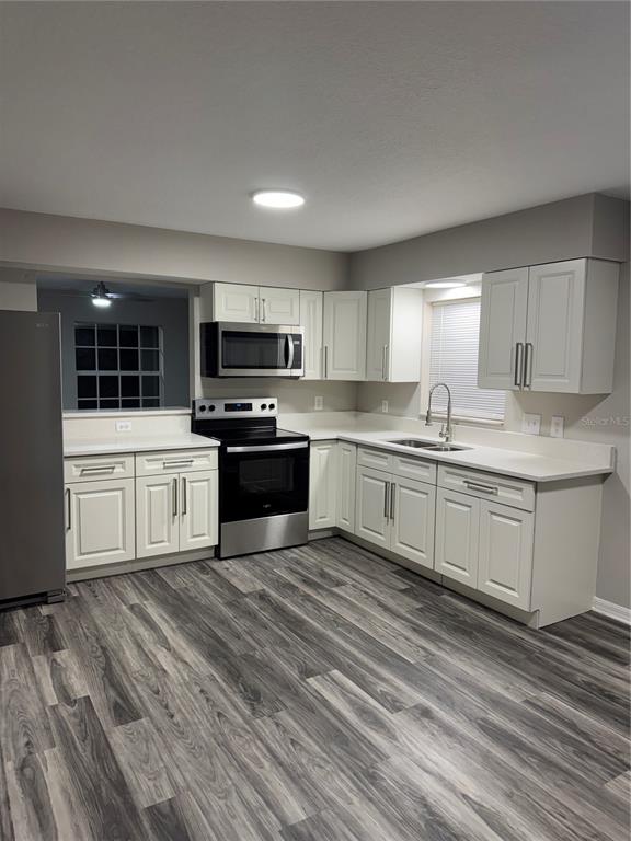 A kitchen with white cabinets, stainless steel appliances, and gray wood-look flooring — 37209 LOCK STREET, DADE CITY, FL