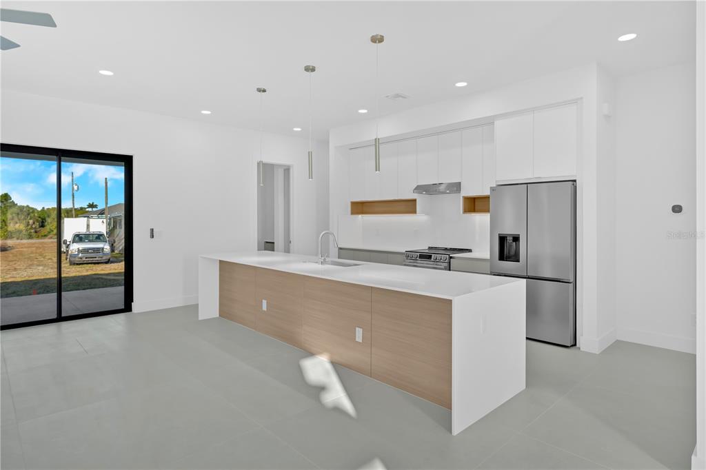 A modern kitchen features a large white quartz island with wood paneling and white cabinetry — 10065 MEMPHIS STREET, PORT CHARLOTTE, FL