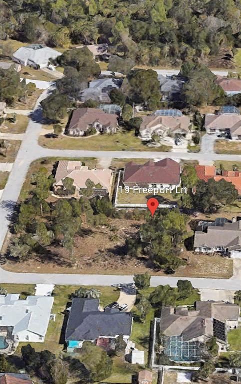 An aerial view shows a vacant residential lot situated between several houses in a neighborhood — 19 FREEPORT LANE, PALM COAST, FL