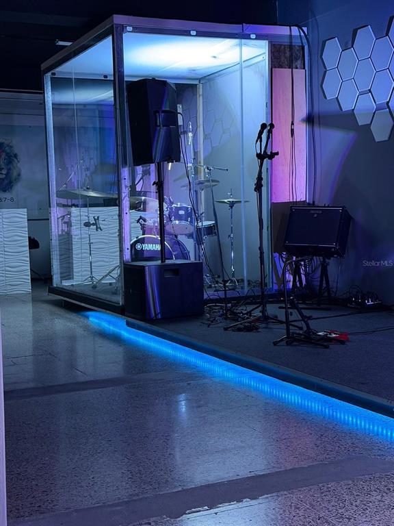 A glass-enclosed drum booth sits on a raised stage with blue LED accent lighting — 100 SECTOR LA CUESTA, LOS JOBOS, HUMACAO, PR