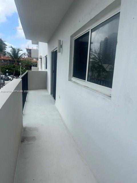 A white balcony with a sliding glass door and a metal railing overlooks a parking area — 6965 Harding Ave # 305, Miami Beach FL 33141, MIAMI BEACH, FL