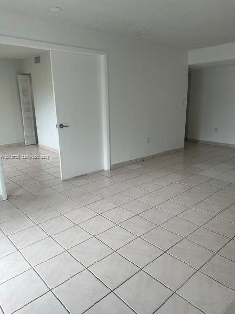 An empty room features light-colored square floor tiles and a white interior door — 6965 Harding Ave # 305, Miami Beach FL 33141, MIAMI BEACH, FL
