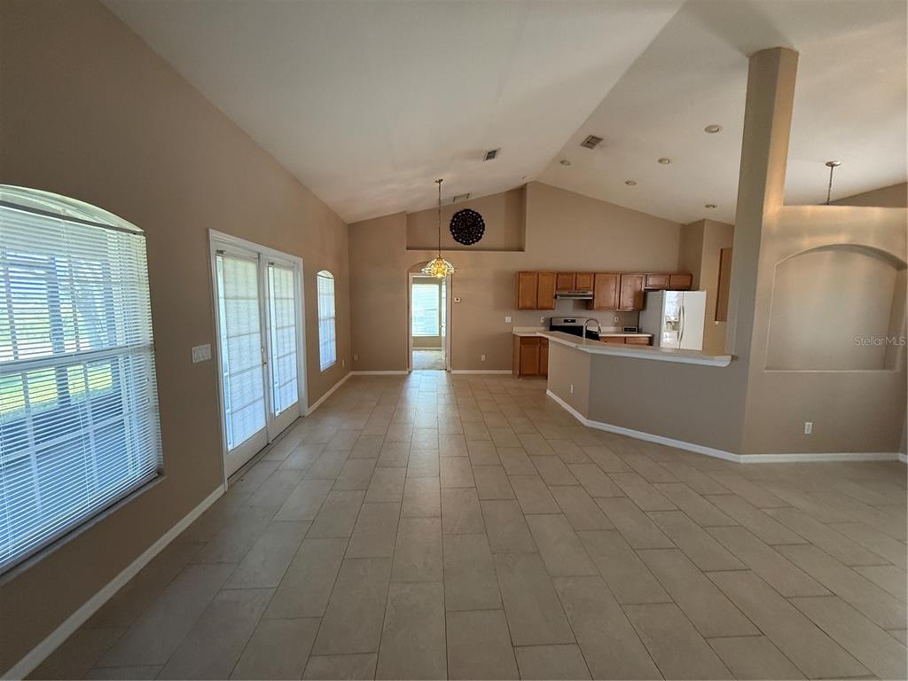 An open-concept living and kitchen area features vaulted ceilings, tile flooring, and light-colored walls — 2735 CEDARIDGE CIRCLE, CLERMONT, FL