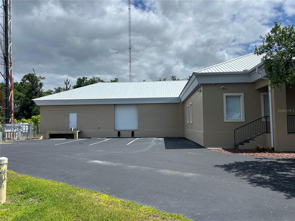 The exterior of a tan commercial building features a loading dock, roll-up door, and parking lot — 1137 SW 7TH ROAD, OCALA, FL