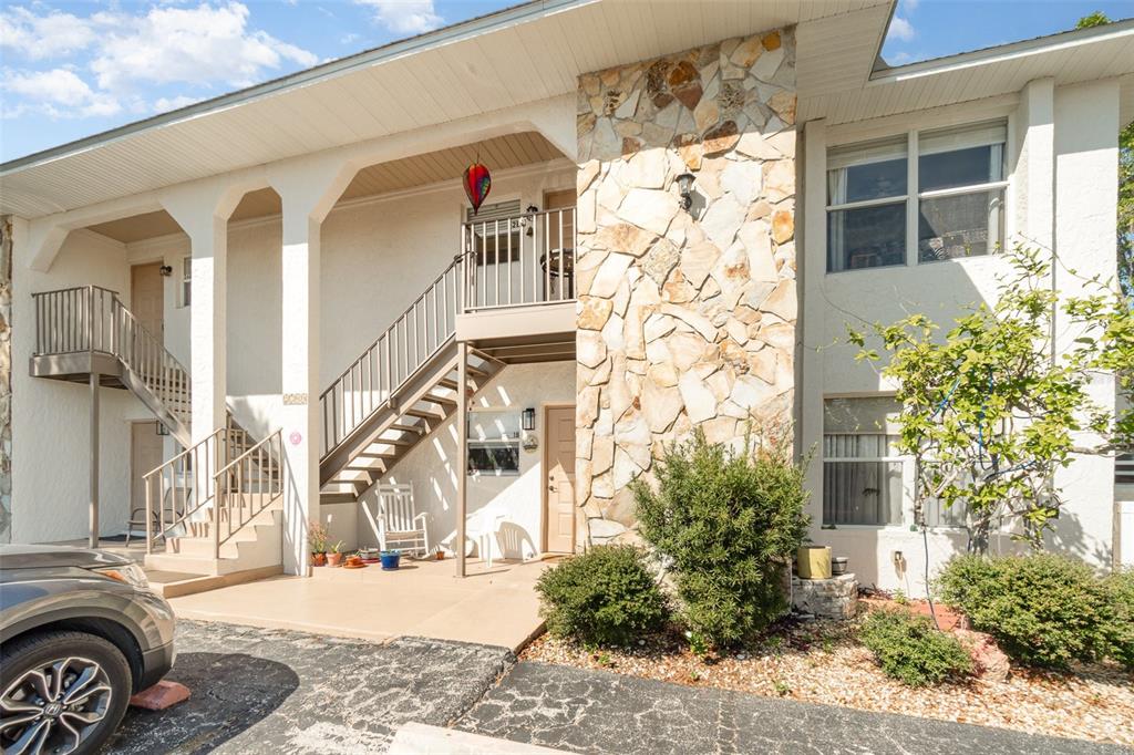 A two-story apartment building exterior features a stone facade, a metal staircase, and a patio — 2700 MAGDALINA DRIVE UNIT 2B, PUNTA GORDA, FL