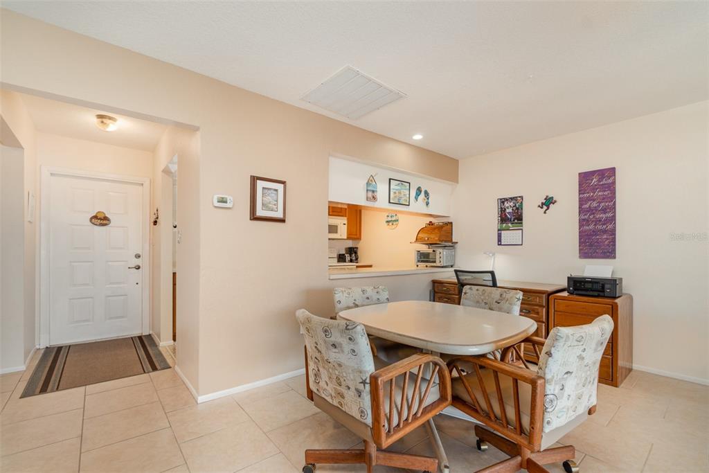 A dining area with a table, four chairs, and a desk adjacent to a kitchen pass-through — 2700 MAGDALINA DRIVE UNIT 2B, PUNTA GORDA, FL
