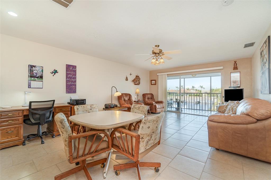 A living room with tile floors, a dining set, a desk, and a sliding glass door — 2700 MAGDALINA DRIVE UNIT 2B, PUNTA GORDA, FL
