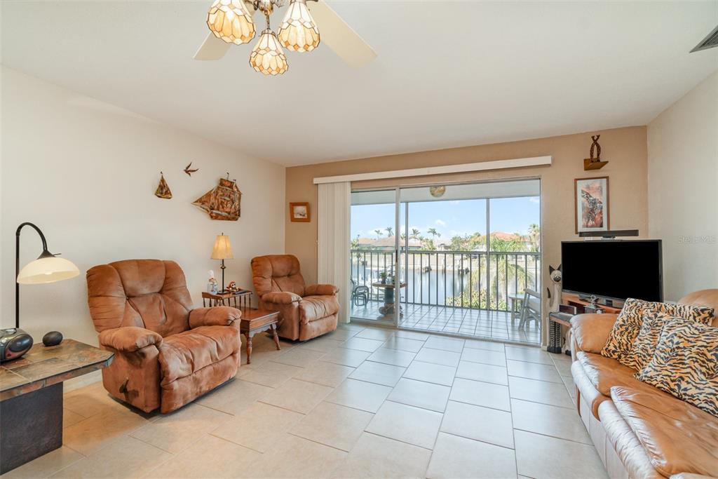 A living room with tile floors, two brown recliners, a sofa, and a balcony view — 2700 MAGDALINA DRIVE UNIT 2B, PUNTA GORDA, FL
