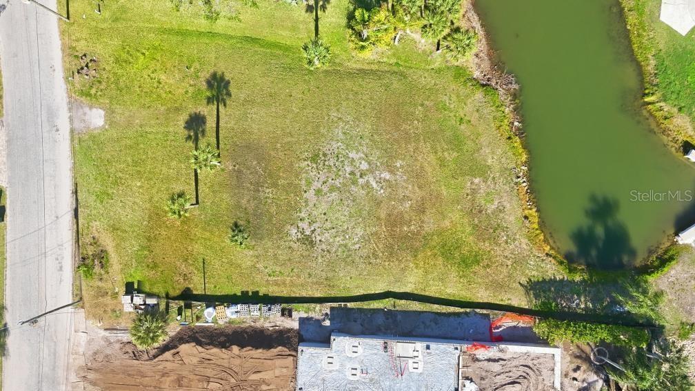 An aerial view shows a vacant, grassy residential lot situated next to a small pond — 0 BAYVIEW PARKWAY, NOKOMIS, FL