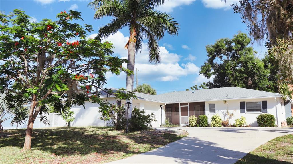 A single-story white house with a palm tree and a driveway in the front yard — 2118 MICHELE DRIVE, SARASOTA, FL