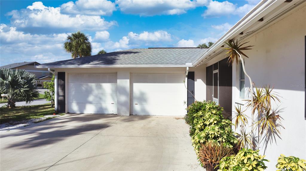 A two-car garage with white doors and a concrete driveway in front of a house — 2118 MICHELE DRIVE, SARASOTA, FL