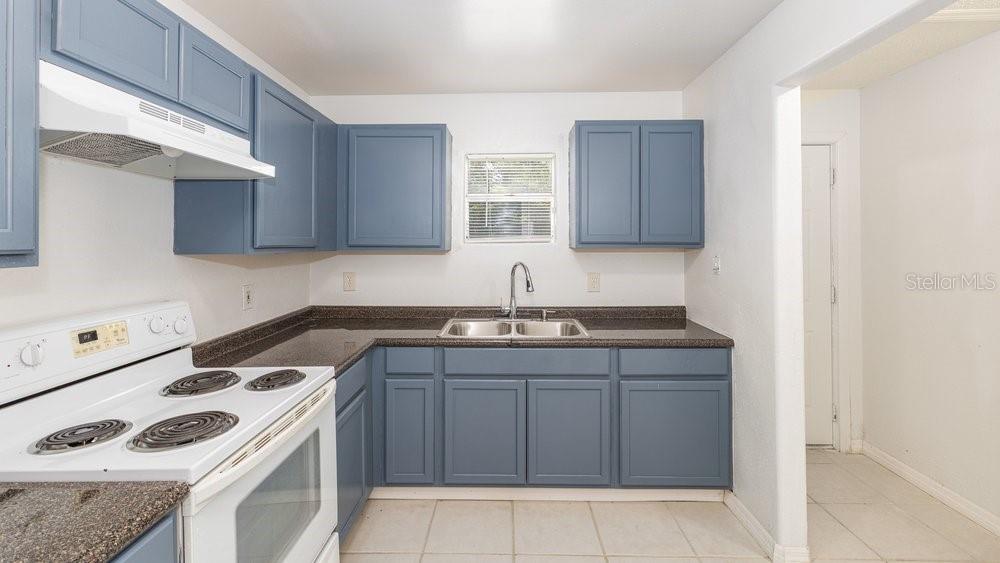 A kitchen with blue cabinets, a white electric stove, and dark countertops — 31128 LOCHMORE CIRCLE, SORRENTO, FL
