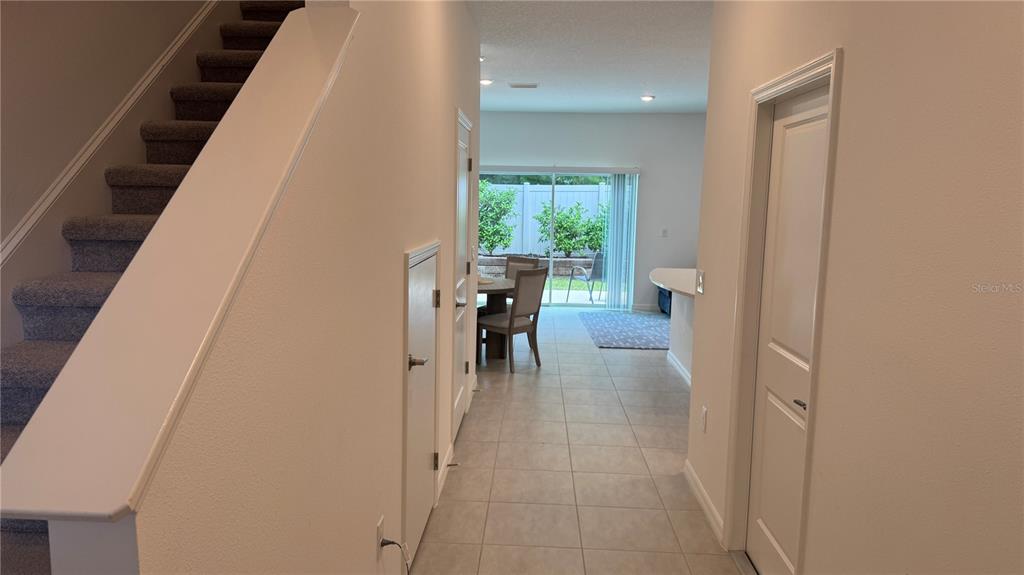 A hallway with carpeted stairs on the left leads to a dining area and sliding doors — 9024 DRIVEN SNOW STREET, SARASOTA, FL