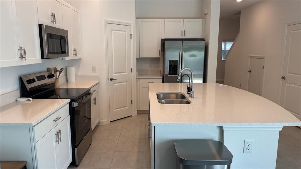 A modern kitchen features white cabinets, stainless steel appliances, and a large central island — 9024 DRIVEN SNOW STREET, SARASOTA, FL