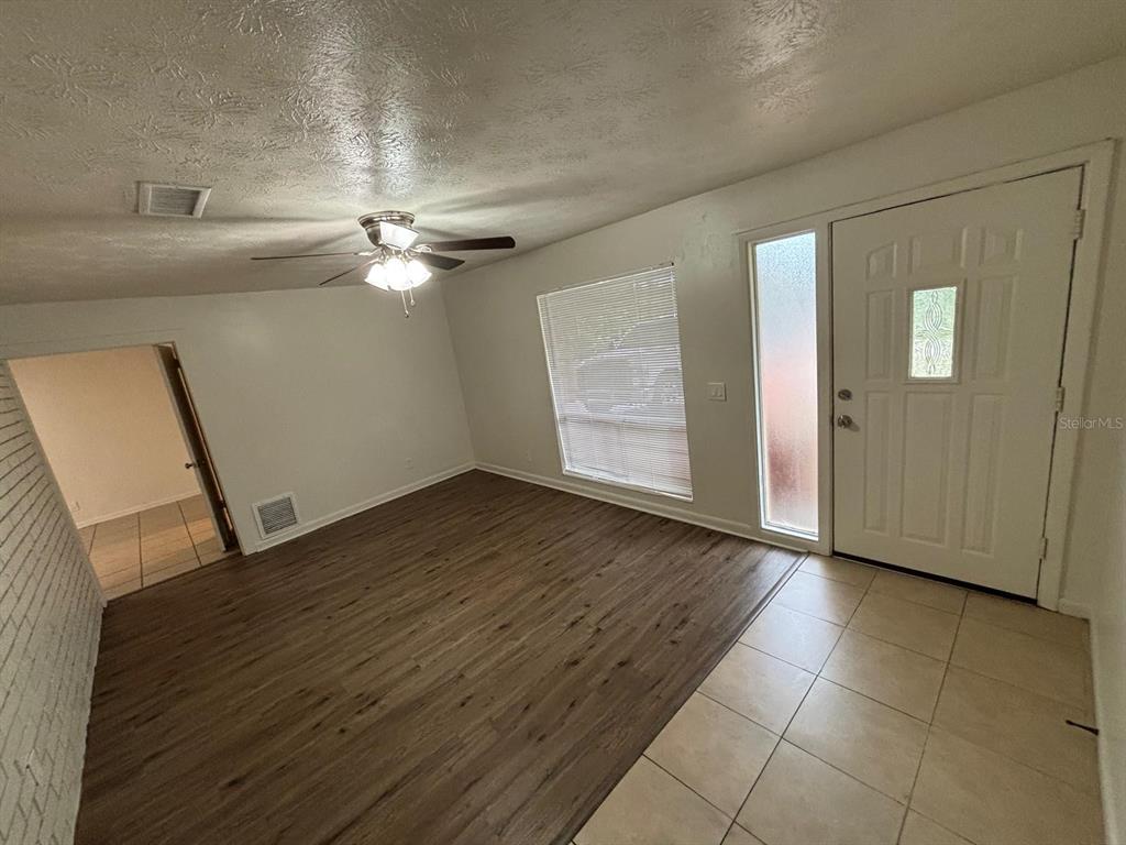 A living room features wood-look flooring, a ceiling fan, and a white front door — 1121 NE 13TH AVENUE, OCALA, FL
