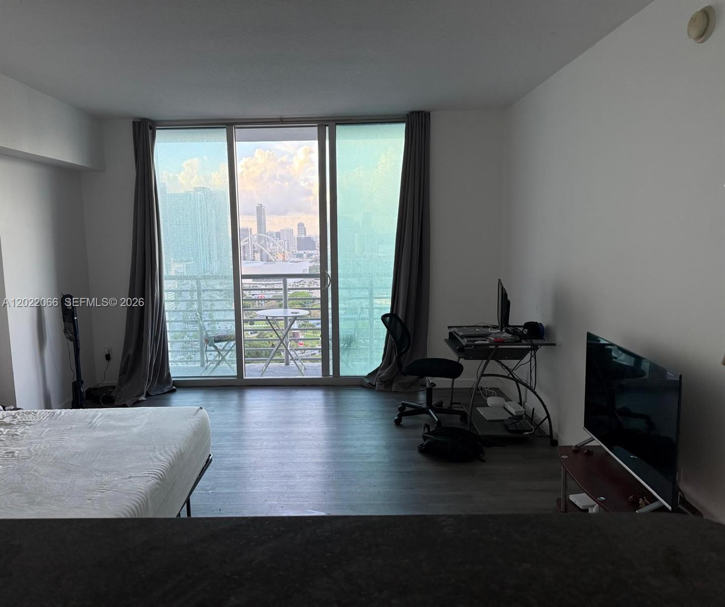 A bedroom features a bed, a desk, a television, and a balcony with city views — 325 S Biscayne Blvd # 3620, Miami FL 33131, MIAMI, FL