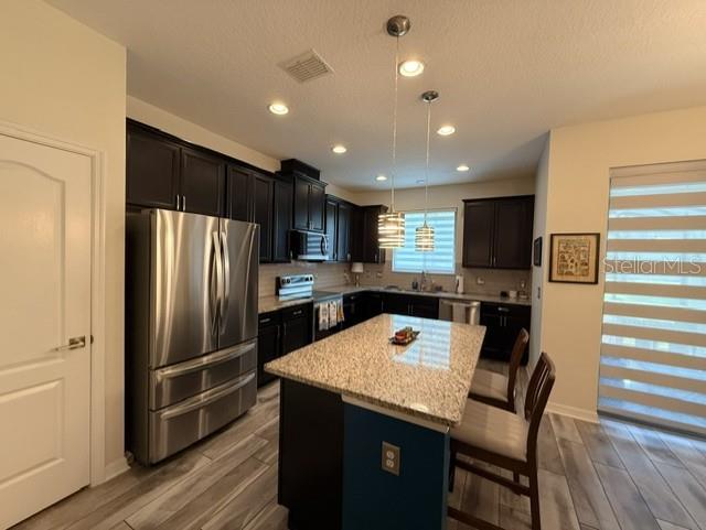 A bathroom with a double vanity, granite countertops, dark cabinets, and a glass-enclosed shower — 11956 SANDS COVE, ORLANDO, FL