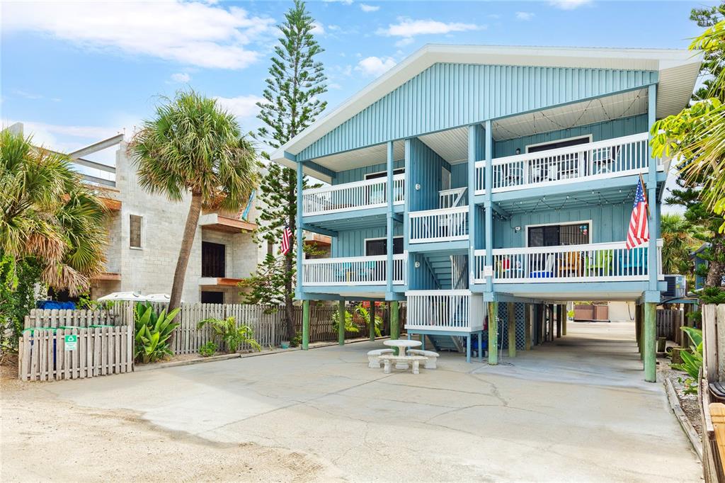 A three-story blue house on stilts features white railings, balconies, and a concrete parking area — 812 GULF BLVD UNIT 3, INDIAN ROCKS BEACH, FL