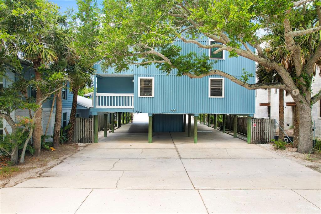 A blue elevated house with a concrete driveway and wooden support pilings — 812 GULF BLVD UNIT 3, INDIAN ROCKS BEACH, FL
